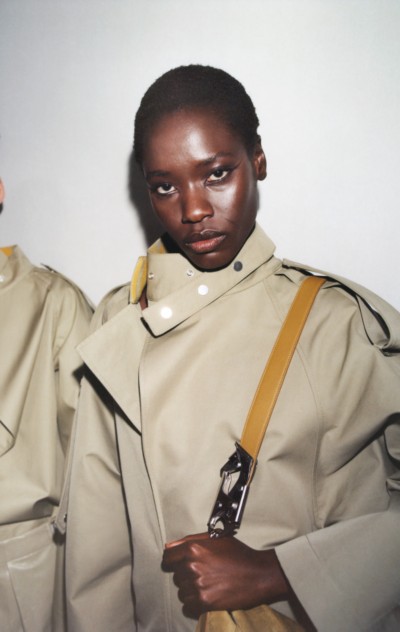 버버리 2023 겨울 캠페인의 헌터 색상 면 트렌치코트와 미모사 색상 스몰 나이트 백을 착용한 모델