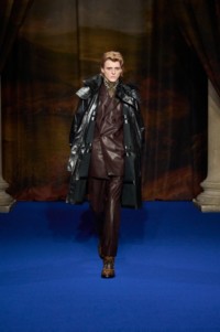 Finn Collins portant une parka en cuir noir et fausse fourrure, une veste et un pantalon de costume en cuir violet Berry, ainsi que des bottes en cuir intarsia Burberry Check coloris Hazel.