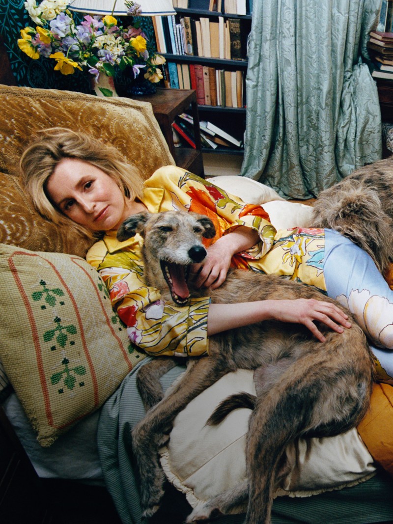 Model laying on sofa, holding dog