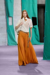 Model wearing mesh polo shirt in cotton and pleated viscose jersey maxi skirt in carrot.