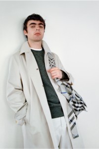 Modelo usando um trench coat Burberry e segurando uma bolsa tote média de malha na cor Lichen.