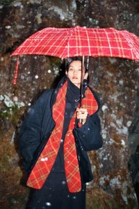 Mannequin portant une veste superposée noire en toile de coton et tenant un parapluie rouge Burberry Check