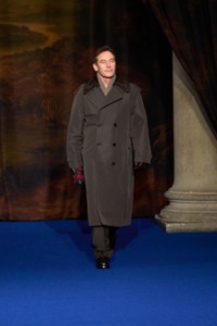 Jason Isaacs usando trench coat de algodão e seda com colarinho de couro xadrez Burberry Check em marrom Shade, suéter com gola xale de lã canelada em bege mesclado e botas Ledger de couro pretas.