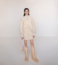 솝 색상의 워싱 나일론 퀼팅 보머 재킷과 스커트, 카메오 색상의 로즈 미니 로킹 홀스 백을 착용한 모델.