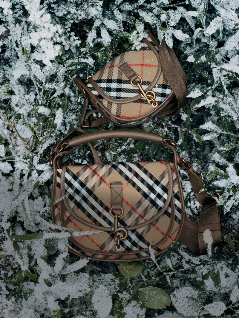 Burberry Festive Campaign featuring two check b-clip bags in different sizes over snowed grass. 