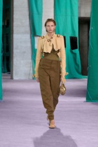 Model wearing trench jacket in vanilla, with ribbed silk top in hemlock and cotton trousers in walrus.