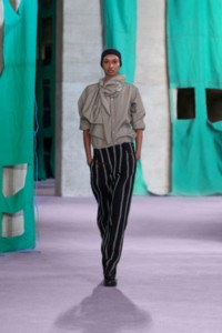 Model wearing striped silk poplin scarf shirt in cellar and striped viscose silk trousers in black and white.