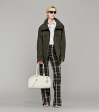 Modella che indossa una giacca con camicia a righe, pantaloni Burberry Check e borsa bowling Shield Twin in pelle