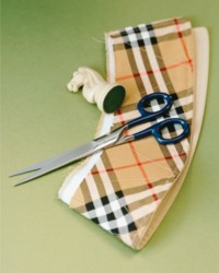 Shot of Burberry Check fabric, with Scissors placed on top with a Horse Chess piece 