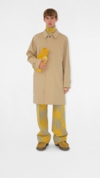 Homem vestindo um trench coat Camdem bege e segurando uma bolsa de água quente amarela