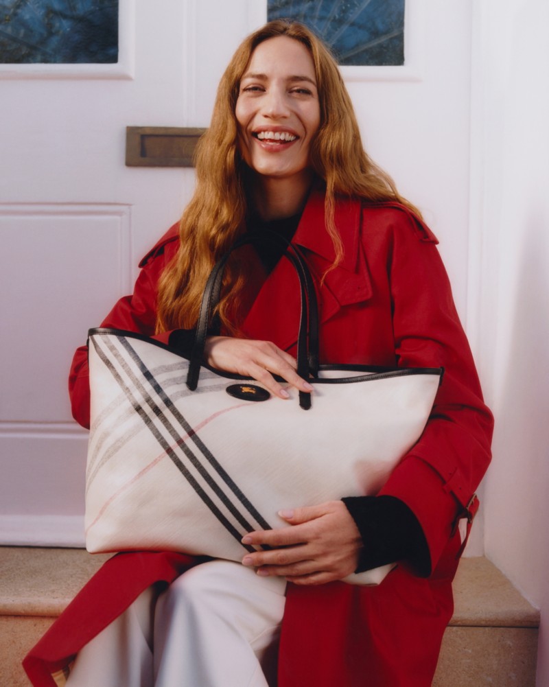 Lizzy Jagger wearing Burberry Long Castleford Trench Coat in colour Currant, holding Medium Highlands Tote in colour Soap