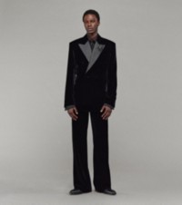 Modelo que luce chaqueta de esmoquin en terciopelo con botonadura doble, camisa y pantalones color negro y zapatos Carlyle en piel color negro 