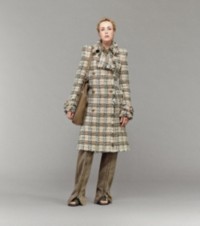 Modelo que luce abrigo a cuadros Burberry Check, pantalones con cremalleras y bolso tote Shield Twin pequeño