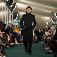 Model wearing trench coat with tailored trousers.