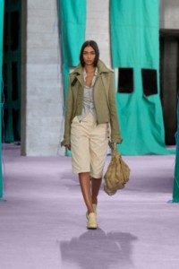 Model wearing bonded linen zip trench jacket in khaki and milk, with striped silk shirt in clam and coated cotton capri trousers in quartz.