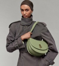 Model in Trenchcoat in der Farbe Shale mit Tasche „Rocking Horse“ aus Leder in Krokodilleder-Optik