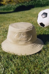Shot of Burberry Knight Stamp Gabardine Bucket Hat on some grass with a Football in the background