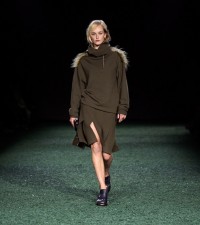 Model in Kleid aus gewalkter Wolle in der Farbe Glen mit Lammfellbesatz und Falten