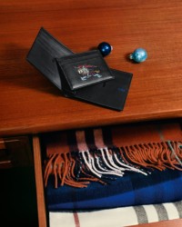 Shot of a Burberry Wallet and Card Case on a wooden table, with an open draw filled with Burberry Check Scarves