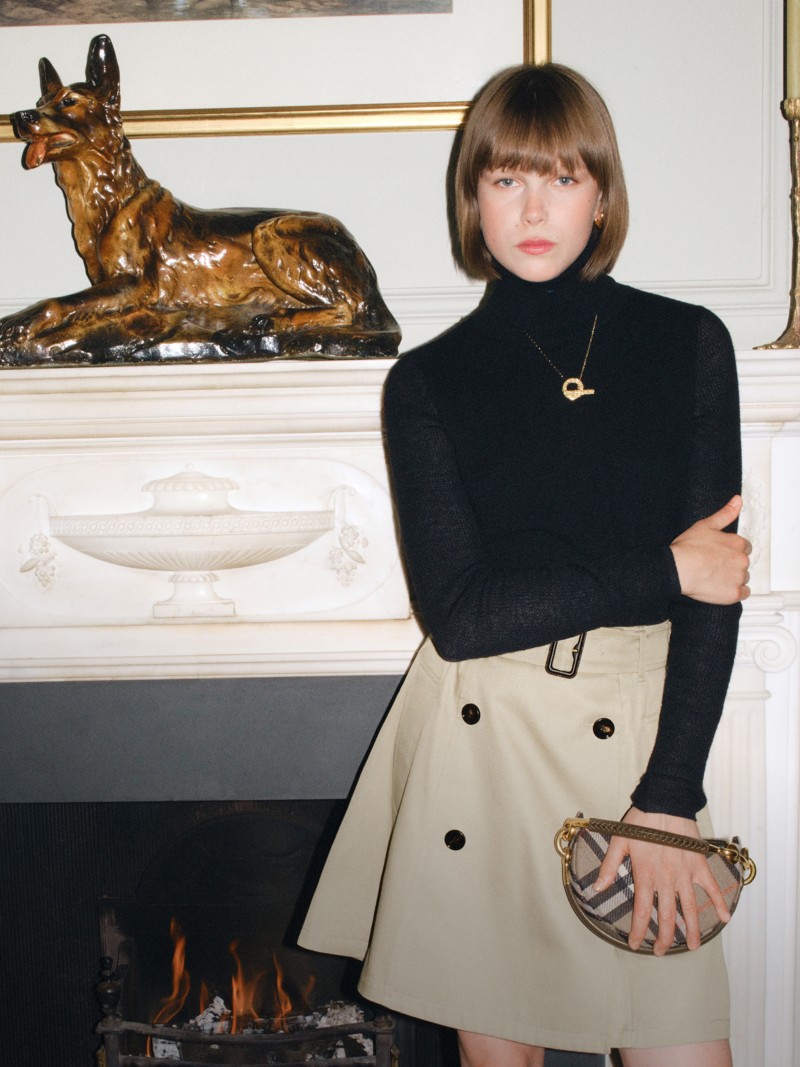 Shot of model wearing Black Polo Neck with Burberry Trench Skirt, holding the Bridle Clutch bag in colour Brush Brown