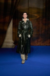 Erin O'Connor wearing leather trench coat in moat green, sunflower silk jacquard pyjama shirt and trousers in taupe beige, and Burberry Check cotton Cameo pumps in brush brown.