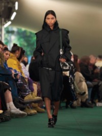 Model in schwarzem Trenchcoat aus einer Seidenmischung