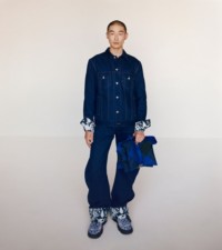 Model in Denim-Jacke und Jeans in Indigoblau und mit der Tasche „Pillow“ im Burberry Check-Karomuster in der Farbe Knight sowie den Schuhen „Creeper“ in der Farbe Salt.