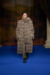 Tae Min Park wearing alpaca wool scarf in biscuit beige, tailored jacket and trousers in pebble beige, paired with intarsia leather boots in truffle brown and Silber Shield earrings.