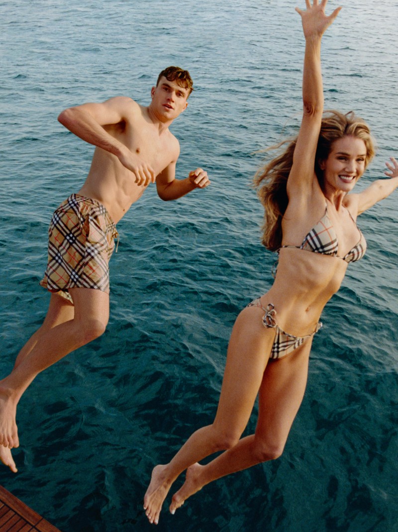 Shot of models jumping into the sea wearing Burberry Check Swimwear