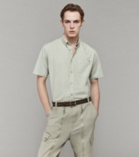 Modelo usando uma camisa Oxford e calças cargo de lona com detalhes de zíper